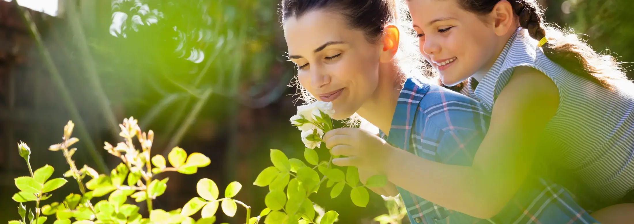 mother and daughter smelling flowers