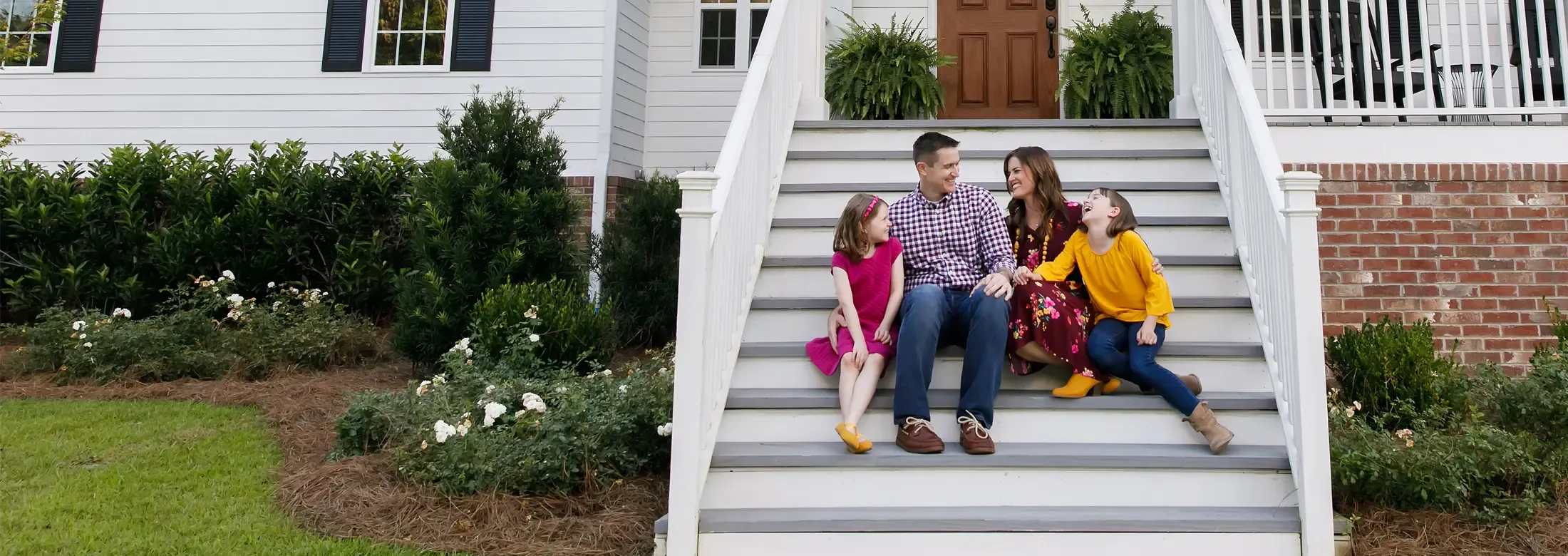 family sitting on front porch laughing