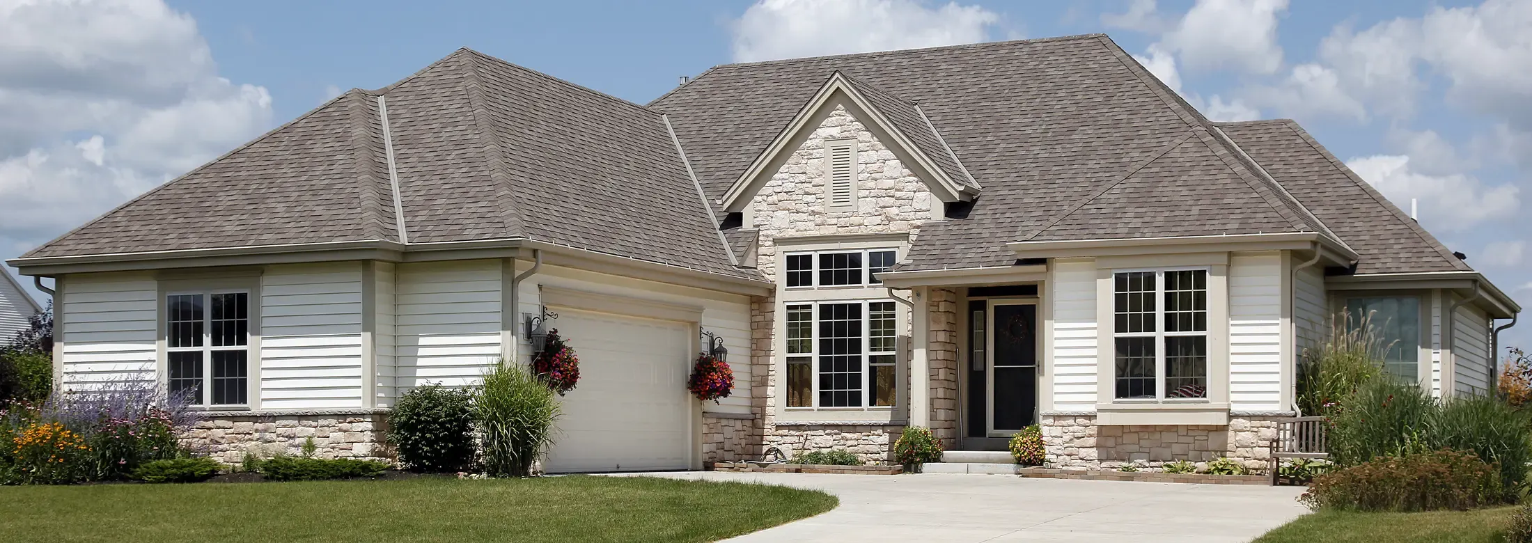 exterior of nice home with white siding and stone walls